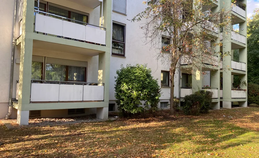 Mehrfamilienhaus mit übereinander liegenden Loggien und Balkonen an einer Rasenfläche im Herbst