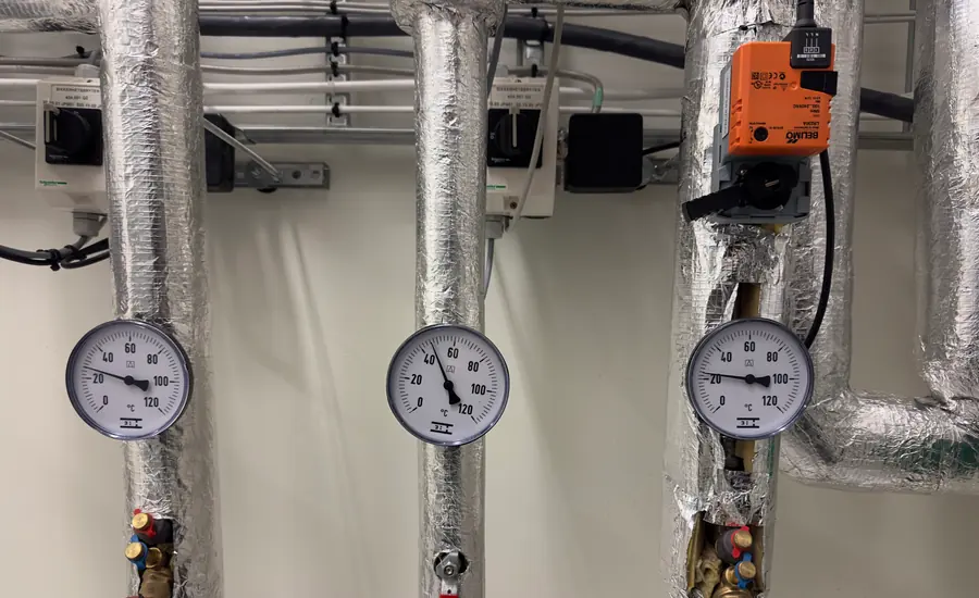 Gedämmte Warmwasserleitungen mit Thermometern und Stellantrieb im Technikraum
