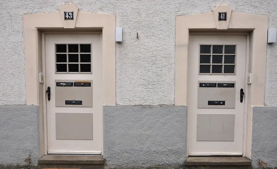 Zwei gleich gestaltete Hauseingangstüren nebeneinander mit den Hausnummern 41 und 43 an einer verputzten Fassade